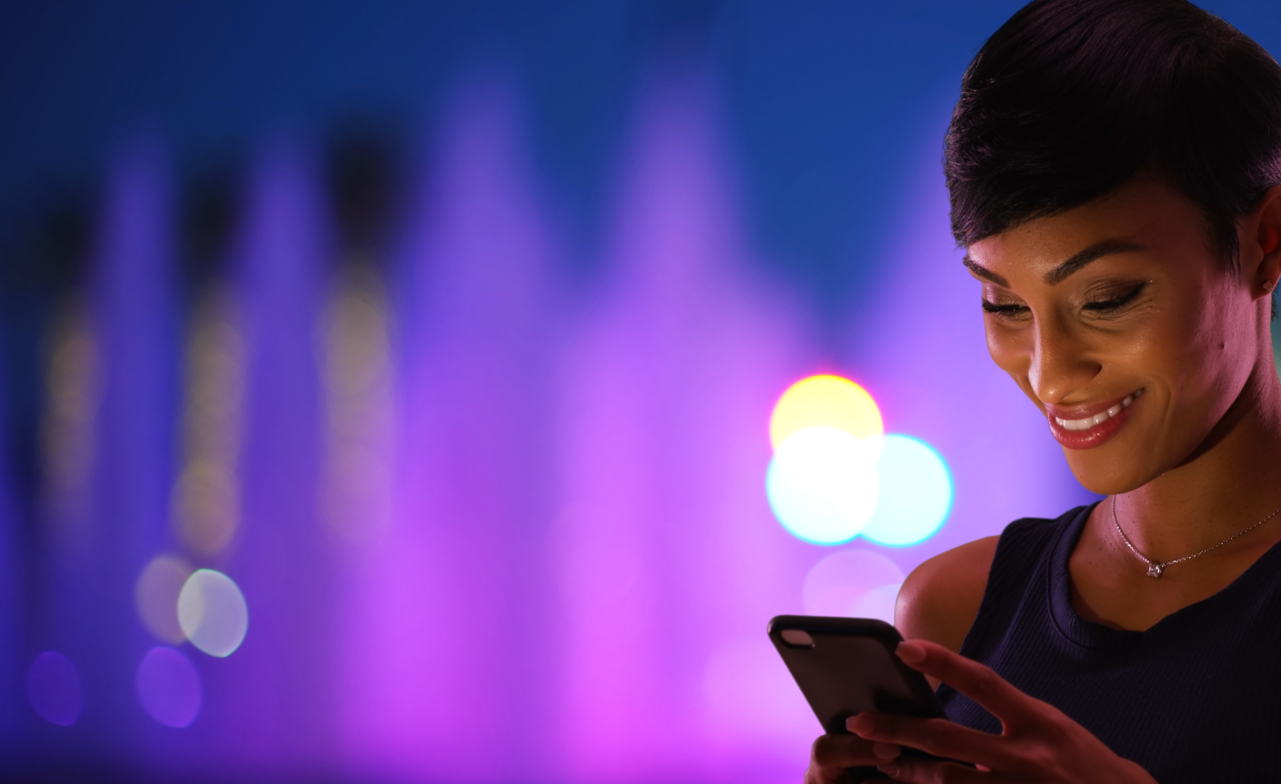 woman looking at phone in front of purple background