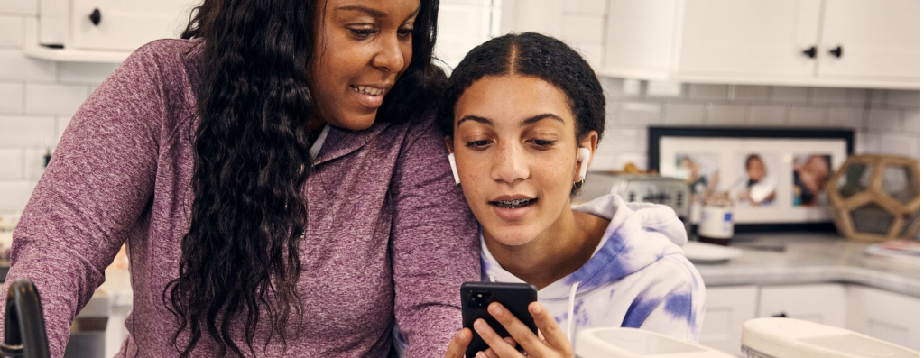 Mom and daughter looking at a smartphone while in the kitchen